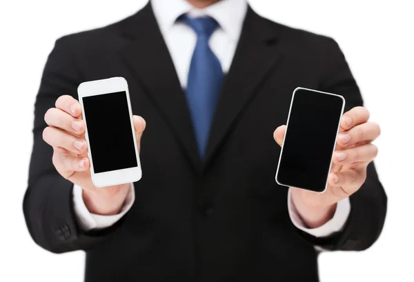 Empresario mostrando teléfonos inteligentes con pantallas en blanco —  Fotos de Stock