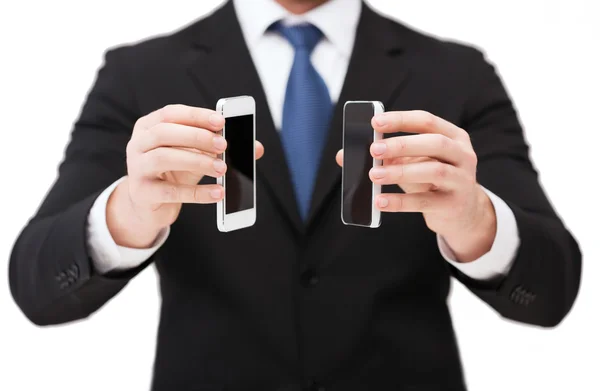 Empresario mostrando teléfonos inteligentes con pantallas en blanco —  Fotos de Stock