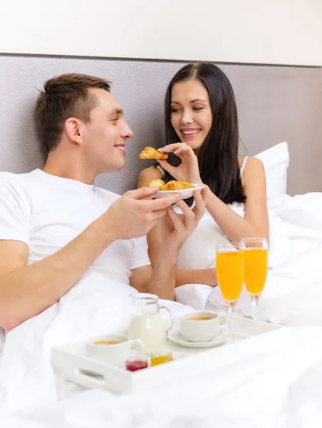 Pareja sonriente desayunando en la cama en el hotel —  Fotos de Stock