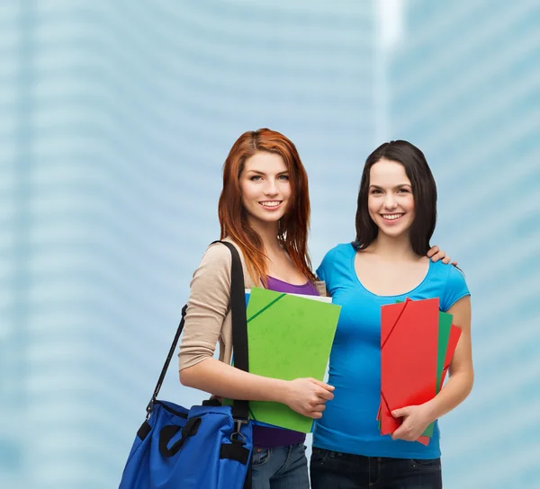 Два улыбающихся студента с сумками и папками — стоковое фото