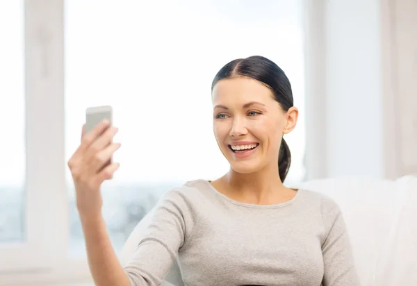 Femme souriante avec smartphone à la maison — Photo