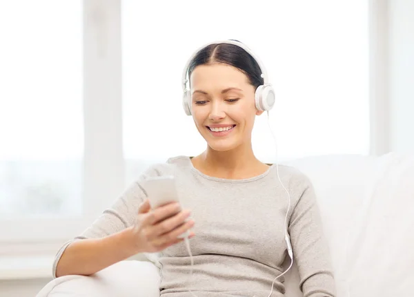 Mujer con smartphone y auriculares en casa —  Fotos de Stock