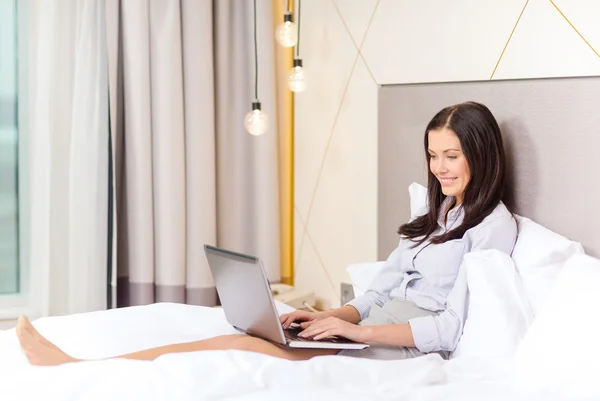 Feliz mujer de negocios con portátil en la habitación de hotel —  Fotos de Stock