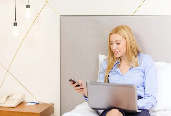 Feliz mujer de negocios con teléfono inteligente en la habitación de hotel —  Fotos de Stock