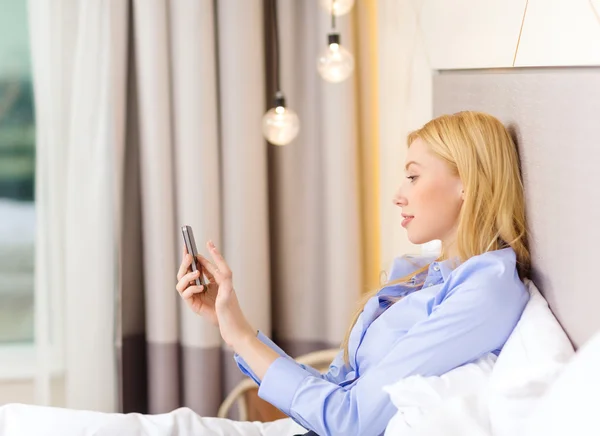 Glückliche Geschäftsfrau mit Smartphone im Hotelzimmer — Stockfoto