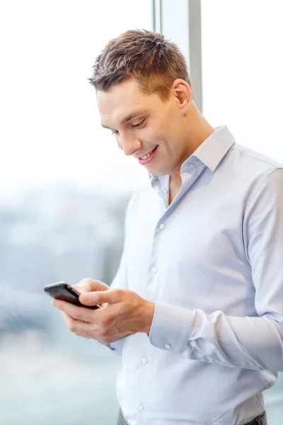 Uomo d'affari sorridente con smartphone in ufficio — Foto Stock