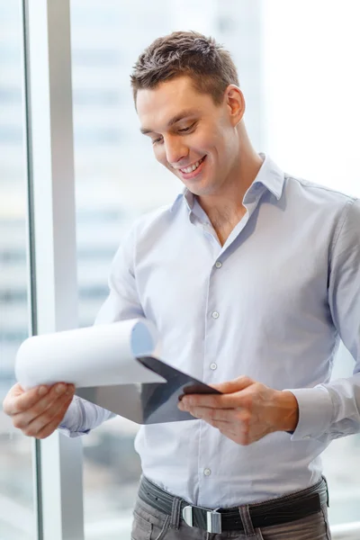 Lächelnder Geschäftsmann mit Klemmbrett im Büro — Stockfoto