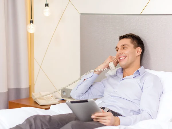 Uomo d'affari con tablet pc e telefono in camera d'albergo — Foto Stock