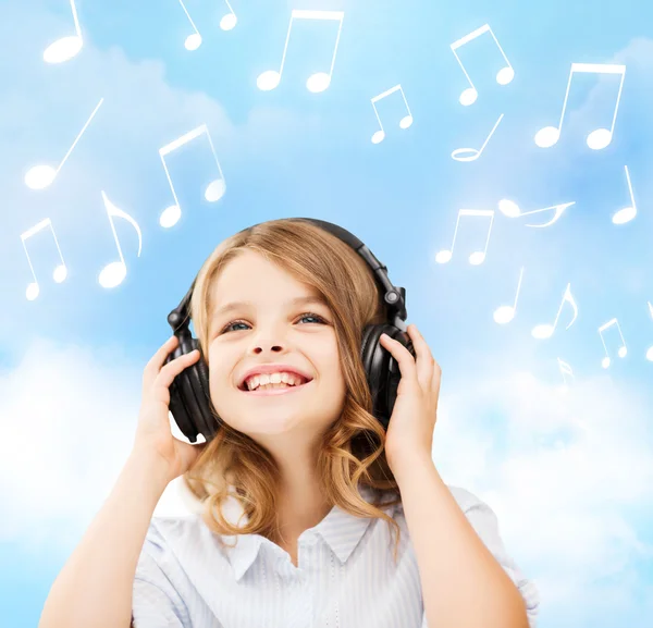 Niña sonriente con auriculares en casa —  Fotos de Stock