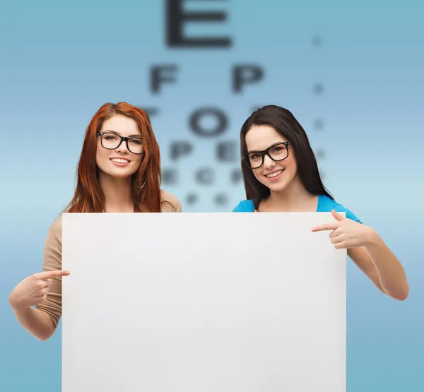 Twee lachende meisjes met brillen en leeg bord — Stockfoto