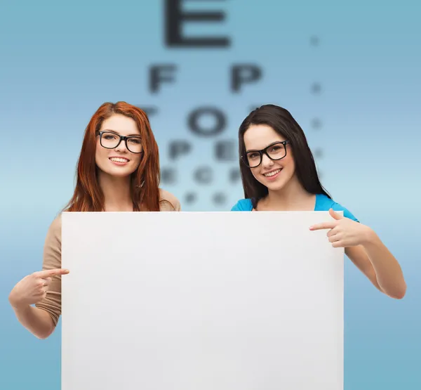 Dos chicas sonrientes con anteojos y pizarra en blanco — Foto de Stock