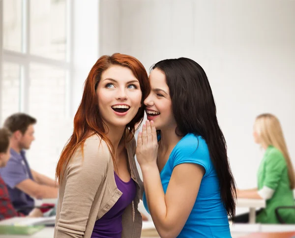 Duas garotas sorridentes sussurrando fofocas — Fotografia de Stock