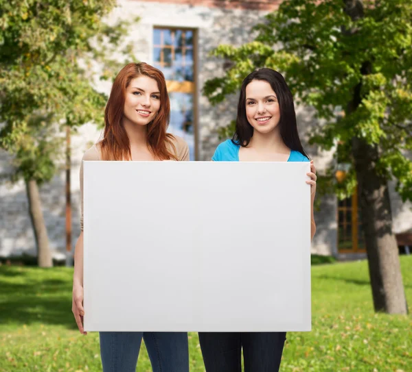 Duas meninas sorridentes com placa branca em branco — Fotografia de Stock