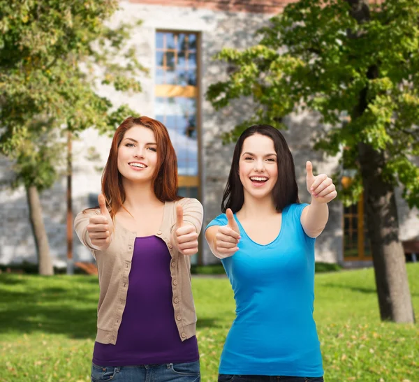 Dvě usmívající dívky ukazuje palec — Stock fotografie