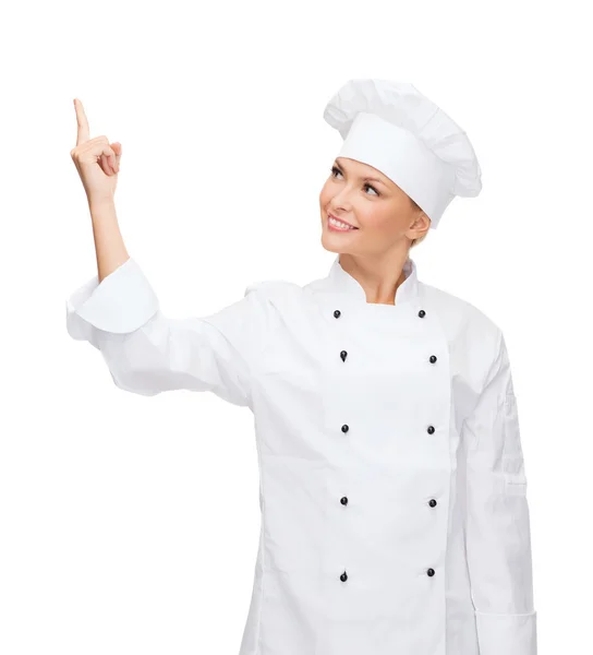 Smiling female chef pointing finger to sonething — Stock Photo, Image