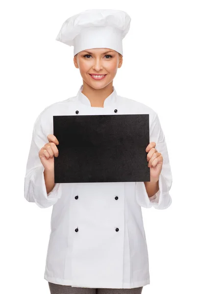 Smiling female chef with black blank paper — Stock Photo, Image