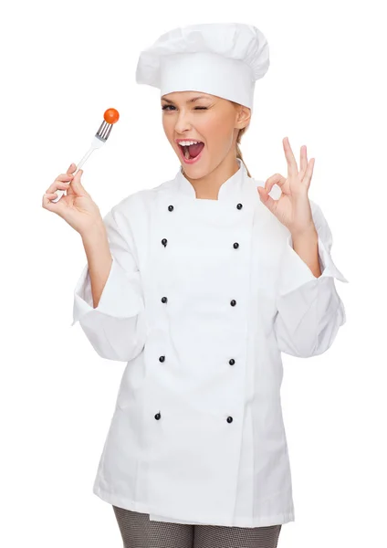 Femme chef souriante avec fourchette et tomate — Photo