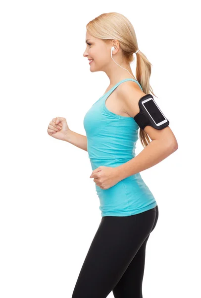 Mujer deportiva corriendo con smartphone y auriculares — Foto de Stock