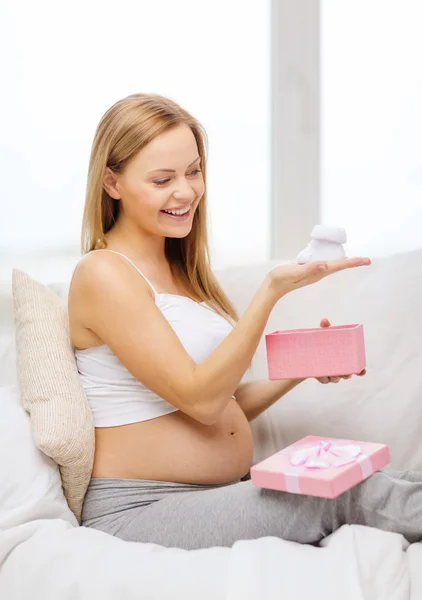 Lächelnde Schwangere mit Geschenkbox und Stiefeln — Stockfoto