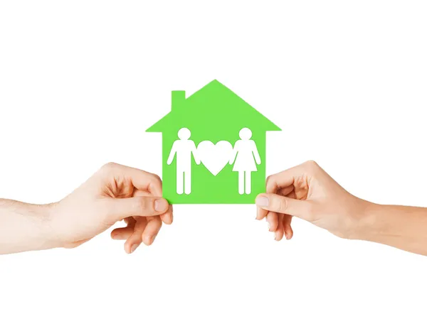 Hands holding green house with family — Stock Photo, Image