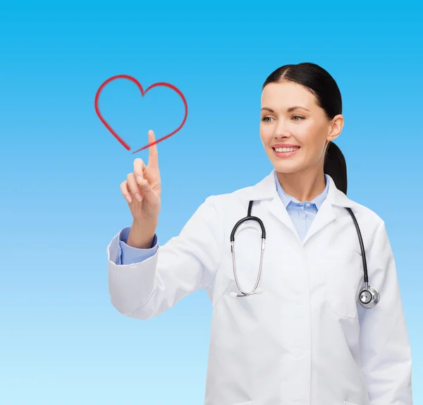 Médica sorridente apontando para o coração — Fotografia de Stock