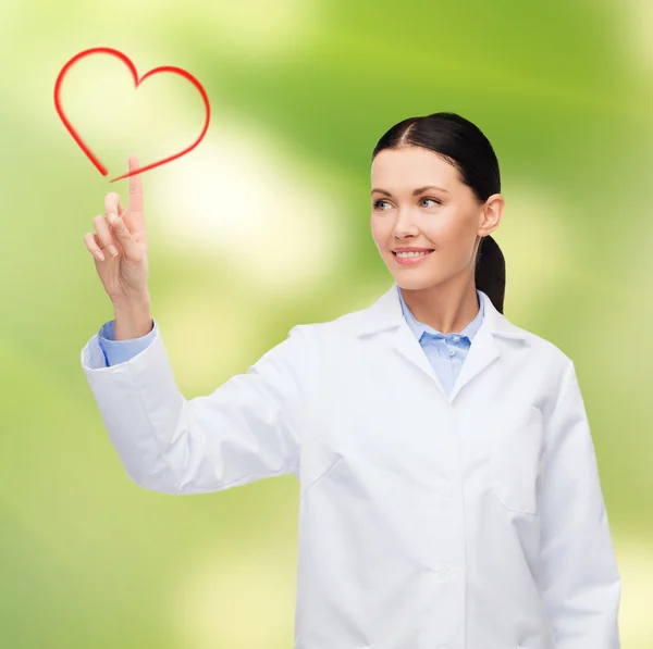 Smiling female doctor pointing to heart — Stock Photo, Image