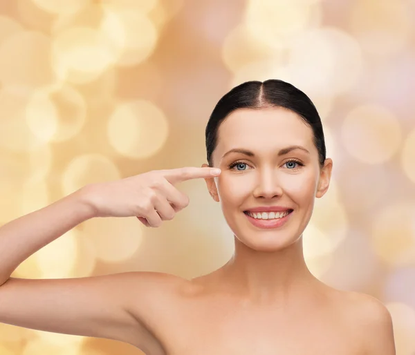 Young calm woman pointing to her eye — Stock Photo, Image