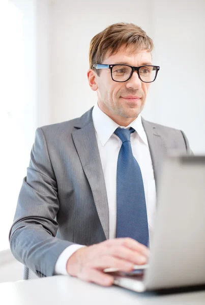 Uomo d'affari in occhiali con computer portatile in ufficio — Foto Stock