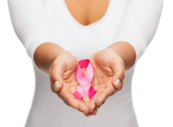 Manos sosteniendo cinta rosa de conciencia de cáncer de mama — Foto de Stock