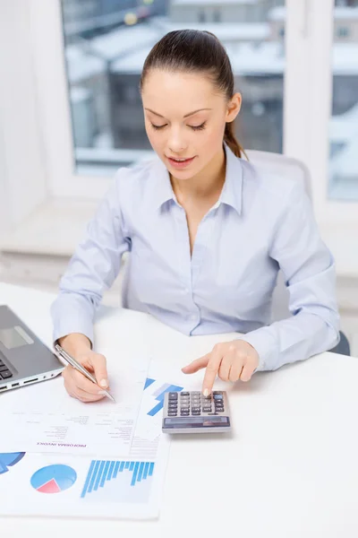 Empresaria con laptop y gráficos en oficina —  Fotos de Stock