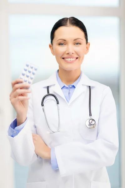 Lachende jonge dokter met pillen en sthethoscope — Stockfoto