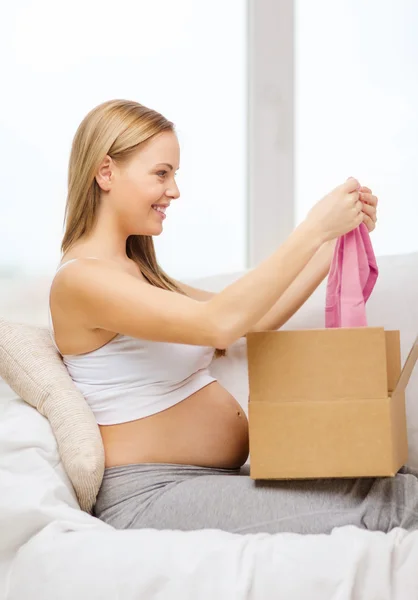 Smiling pregnant woman opening parcel box — Stock Photo, Image