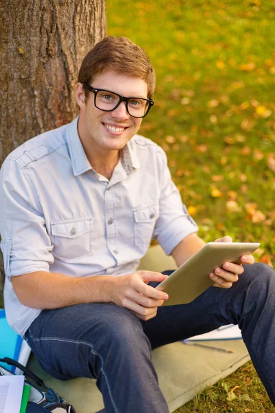 Estudante do sexo masculino sorridente em óculos com tablet pc — Fotografia de Stock