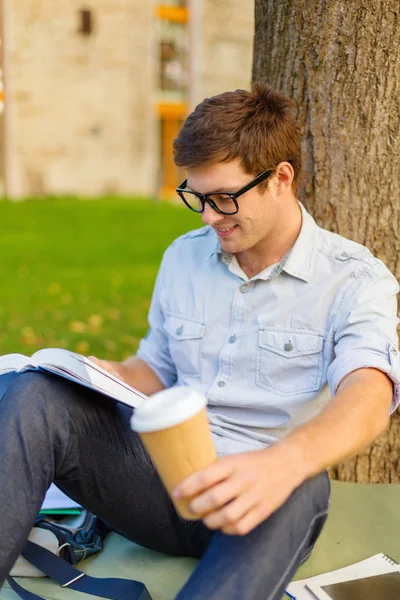 Teenager reading book with take away coffee — Stock Photo, Image