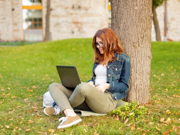 Adolescente sorridente in occhiali con laptop — Foto Stock