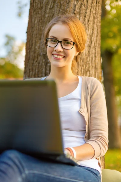 Lachende tiener in bril met laptop — Stockfoto