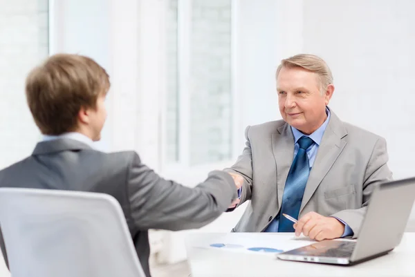 Older man and young man shaking hands in office — Stock Photo, Image