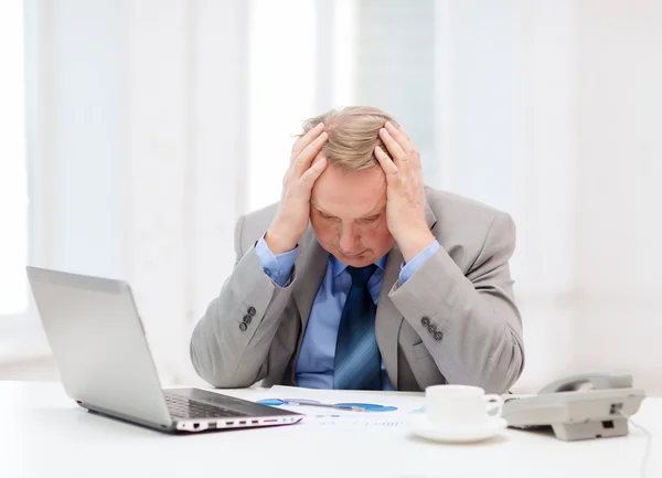 Upset older businessman with laptop and telephone — Stock Photo, Image