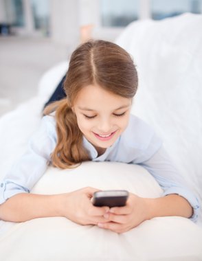 Smiling girl with smartphone at home
