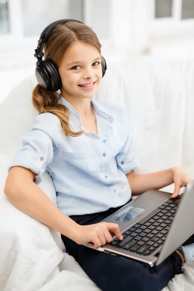 Meisje met laptopcomputer en koptelefoon thuis — Stockfoto