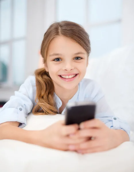 Lachende meisje met smartphone thuis — Stockfoto