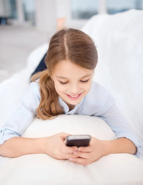 Lachende meisje met smartphone thuis — Stockfoto