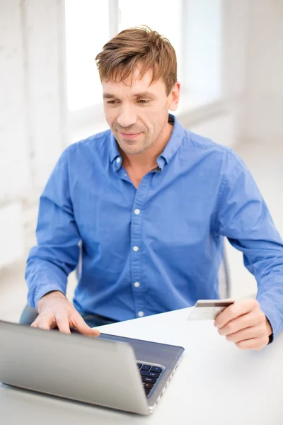 Uomo con computer portatile e carta di credito a casa — Foto Stock