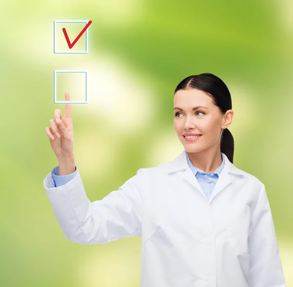 Smiling female doctor pointing to checkbox — Stock Photo, Image