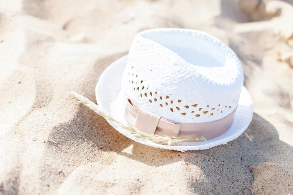 Biały kapelusz słomkowy leżącego w piasku na plaży — Zdjęcie stockowe