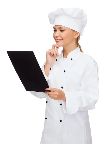 Lachende vrouwelijke chef-kok met zwarte blanco papier — Stockfoto