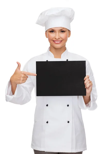 Smiling female chef with black blank paper — Stock Photo, Image