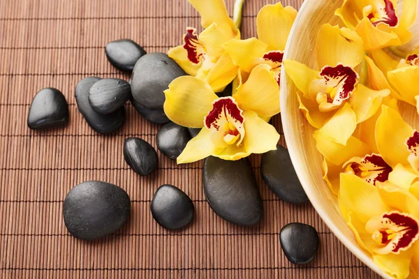 Massage stones with flowers on mat — Stock Photo, Image