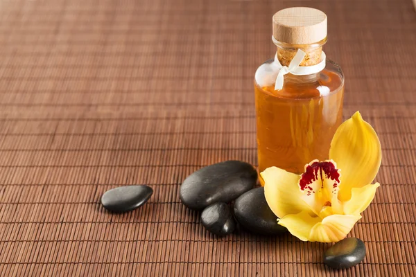 Óleo essencial, pedras de massagem e flor de orquídea — Fotografia de Stock