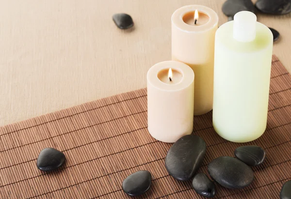 Shampoo bottle, massage stones and candles — Stock Photo, Image